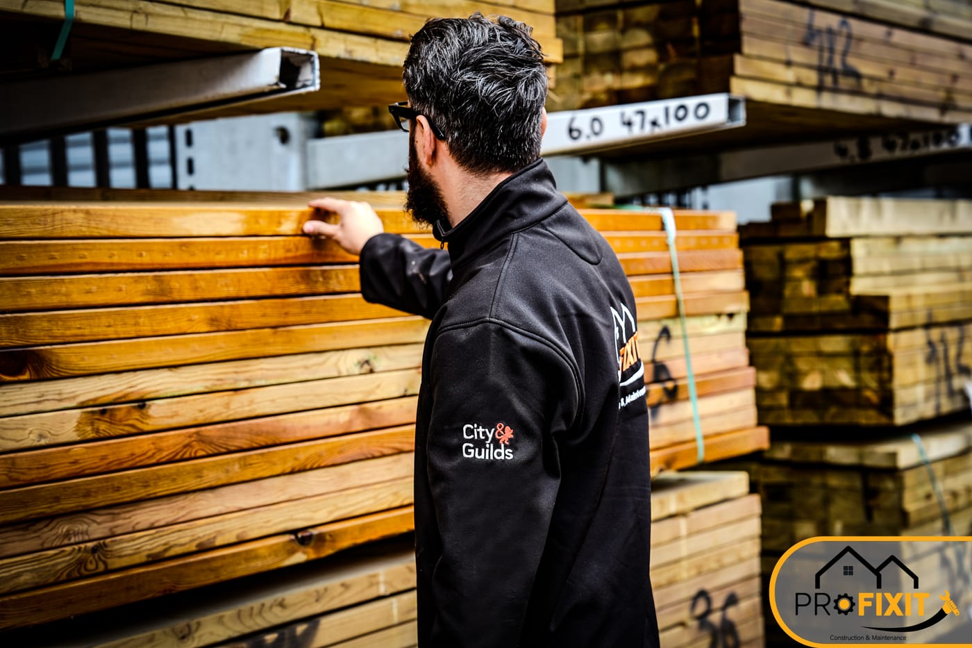 A Pro Fixit worker selecting boards from stacked timber.